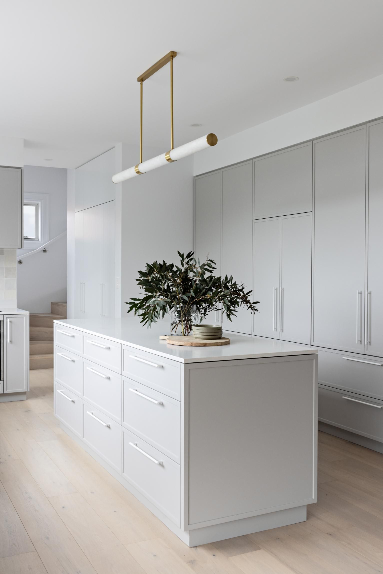 A Kitchen with White Cabinets and A Large Island with A Plant on It — Goode By Design in Unanderra, NSW
