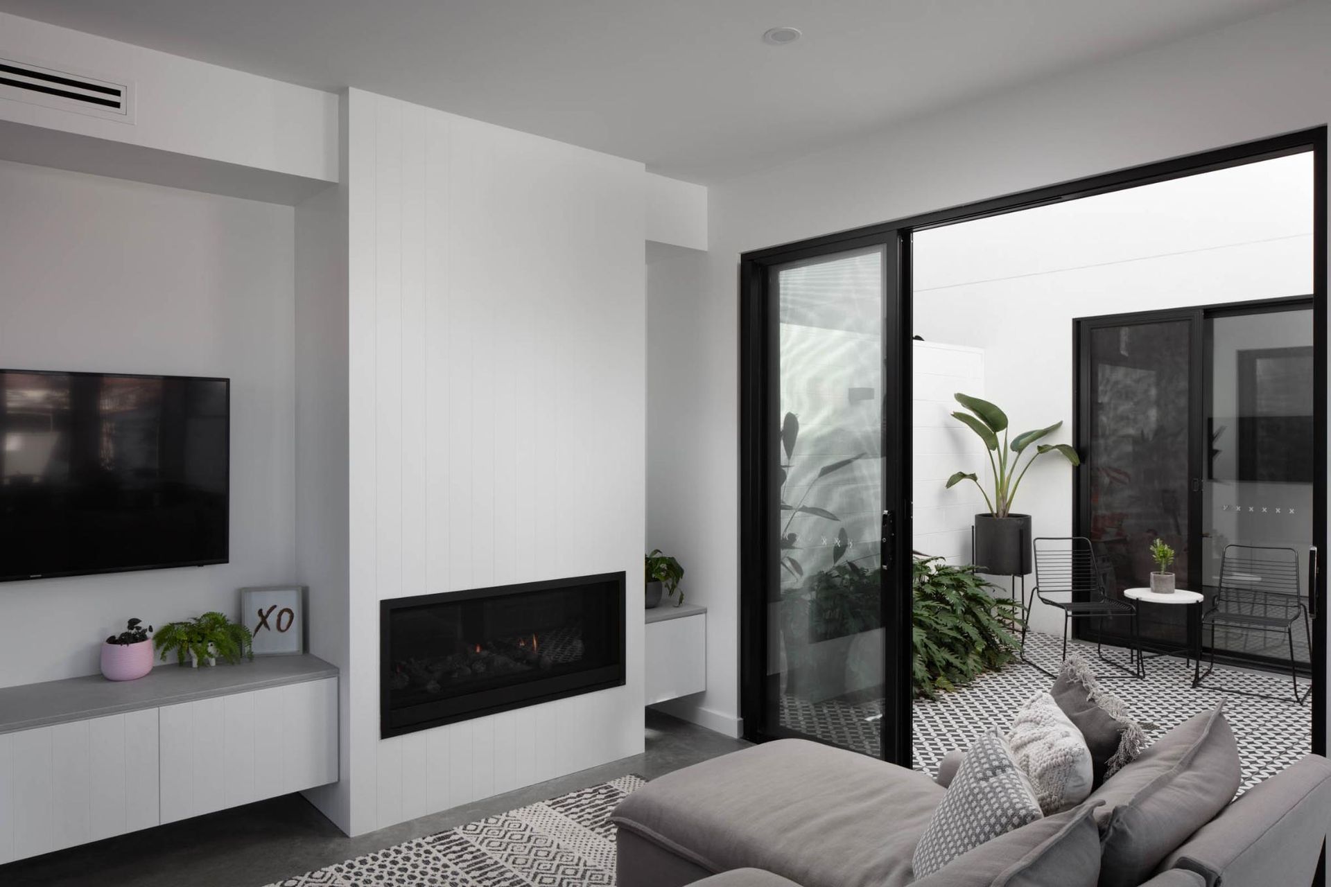 A Living Room with A Couch, Television, Fireplace and Sliding Glass Doors — Goode By Design in Unanderra, NSW