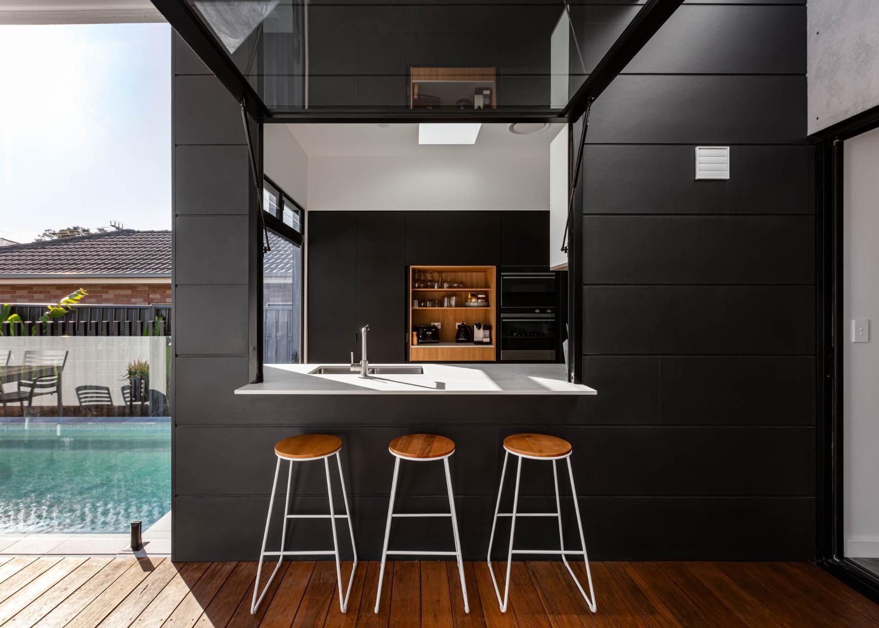A Kitchen with Three Stools and A Swimming Pool in The Background — Goode By Design in Unanderra, NSW