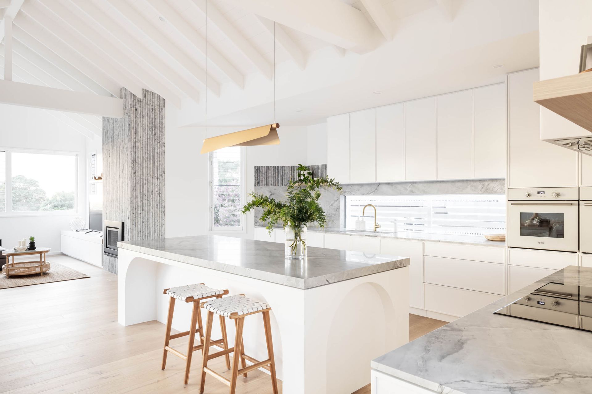 A Kitchen with White Cabinets, a Large Island, and Stools — Goode By Design in Unanderra, NSW