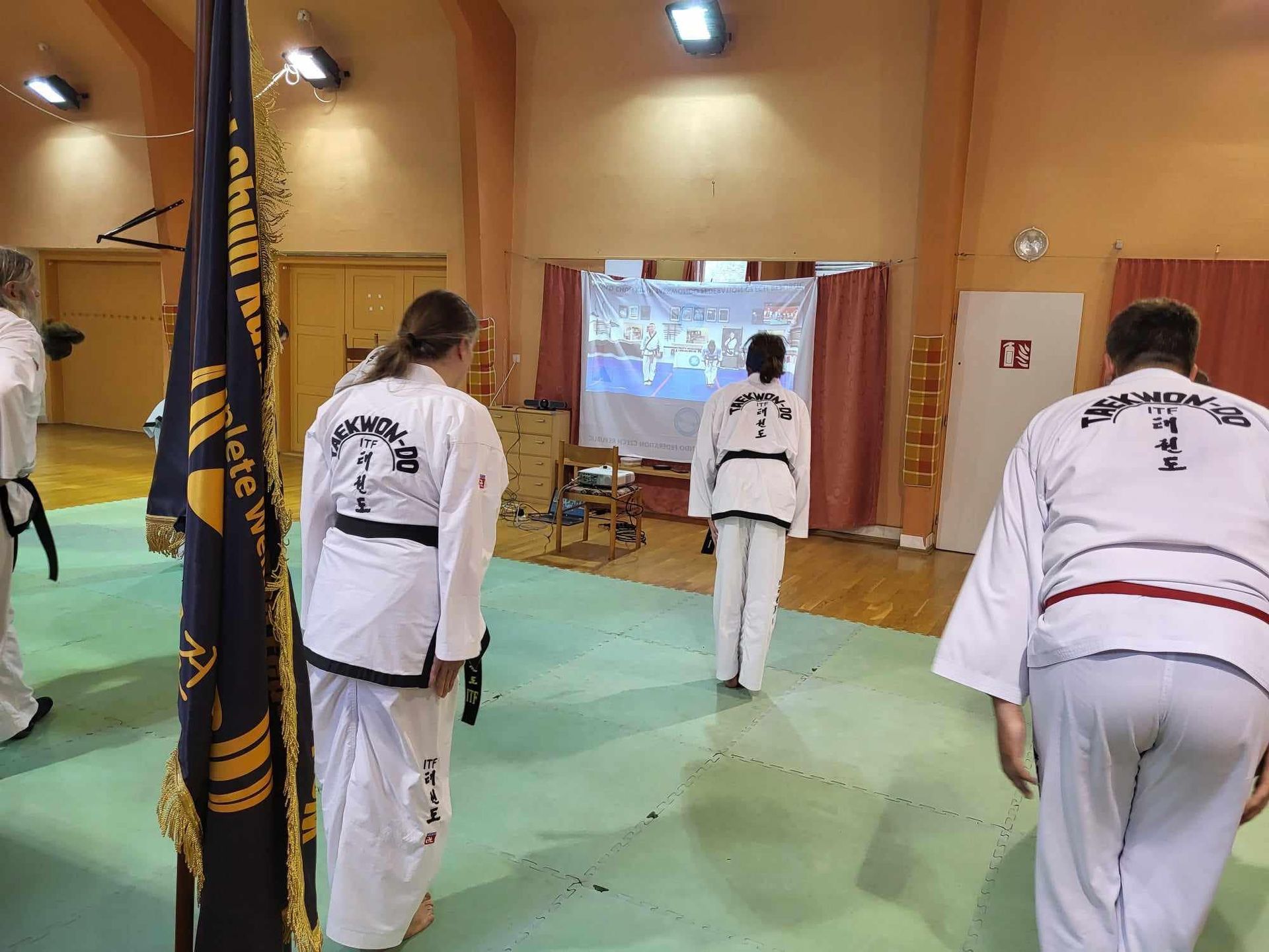 A group of people in karate uniforms are standing in a gym.