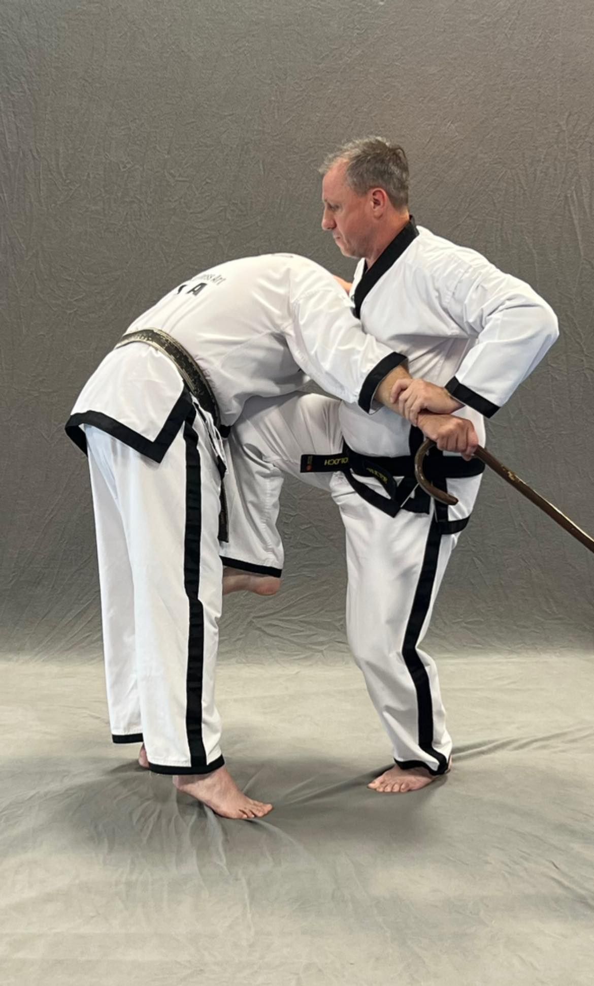 Two men are practicing martial arts on a mat.