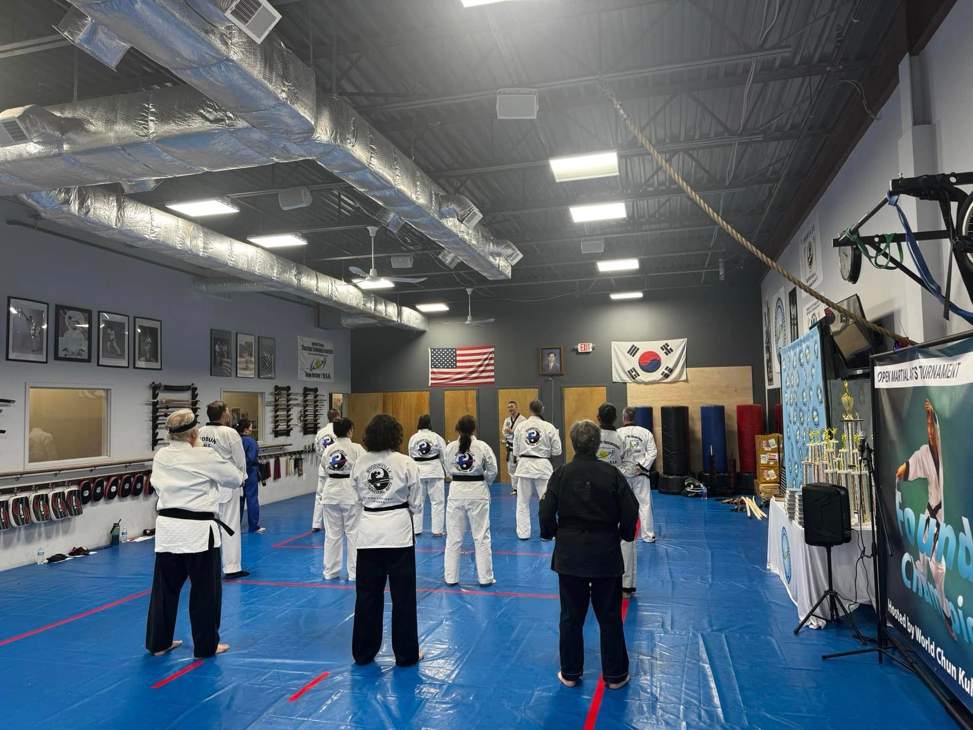 A group of people are standing on a blue mat in a gym.