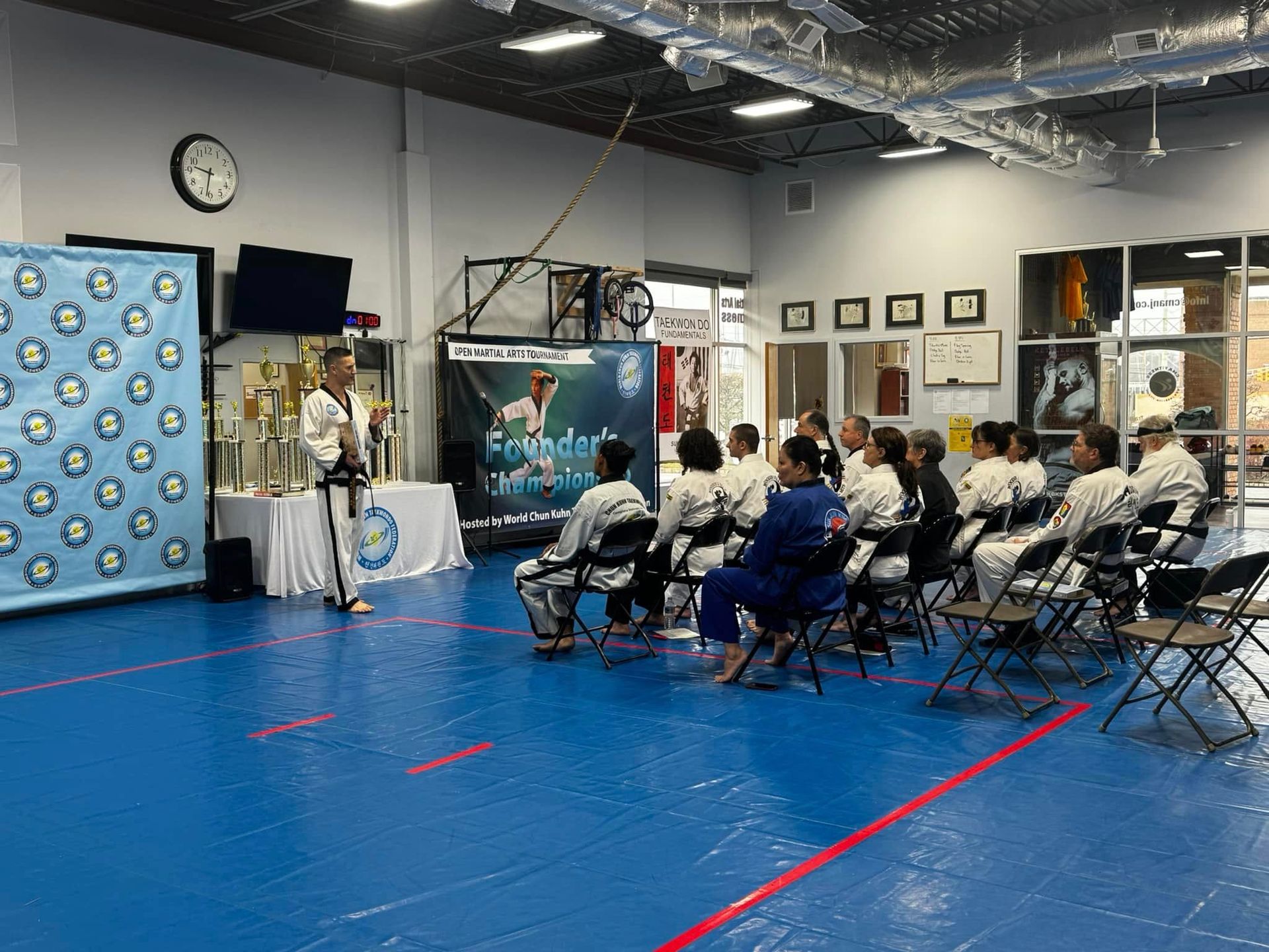A group of people are sitting in chairs in a gym.