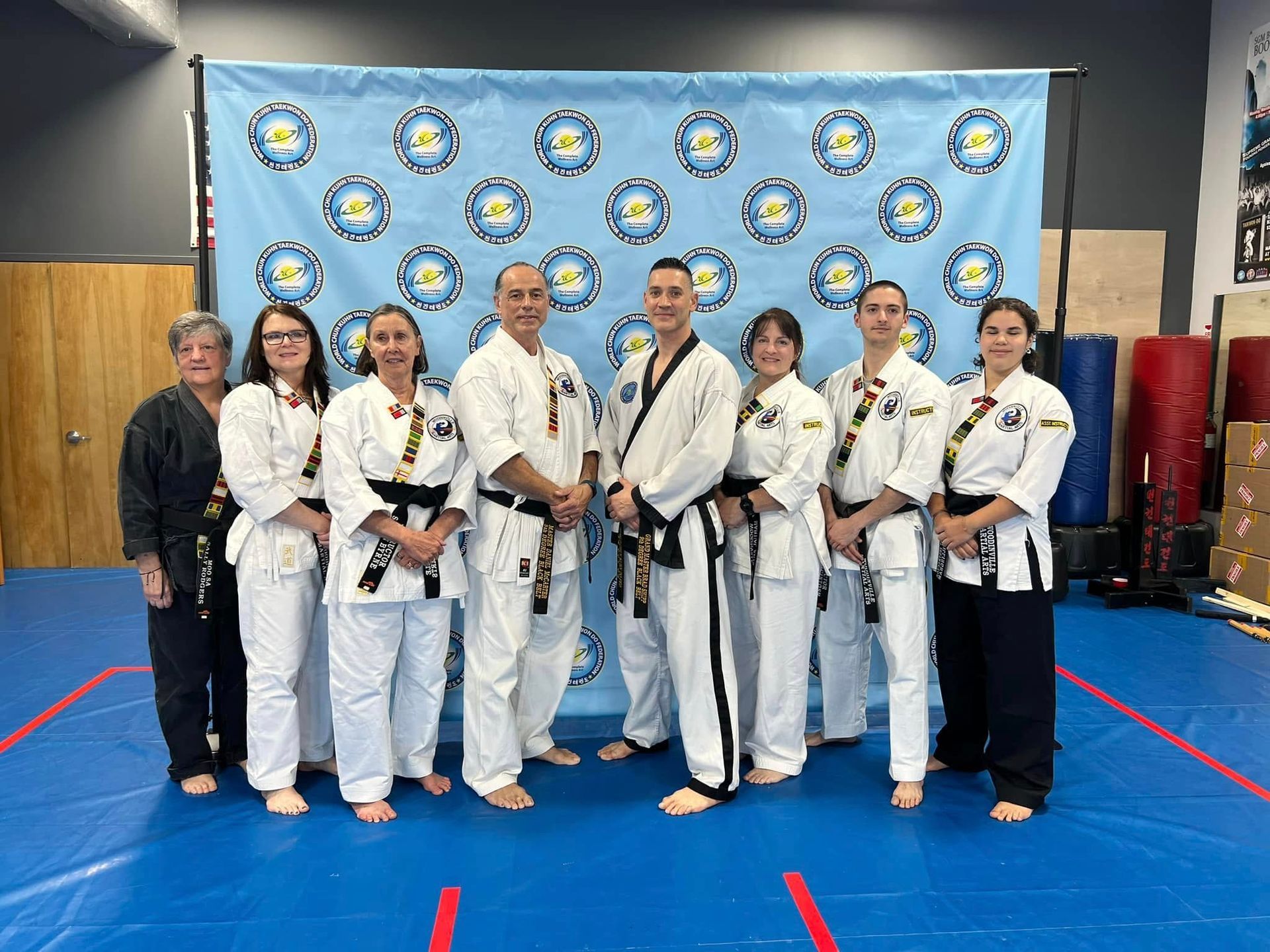 A group of people in karate uniforms are posing for a picture in a gym.