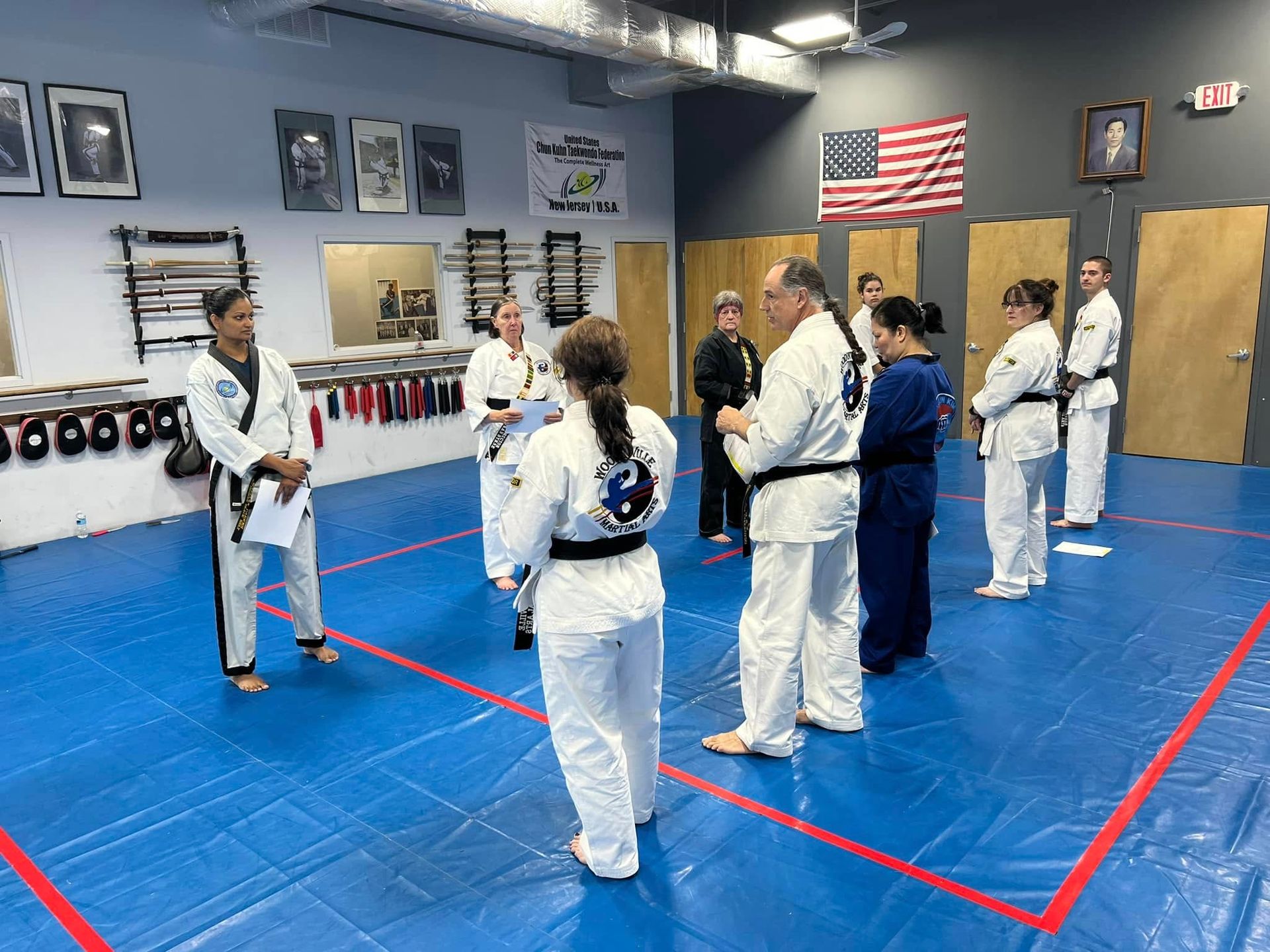 A group of people are standing in a karate class in a gym.