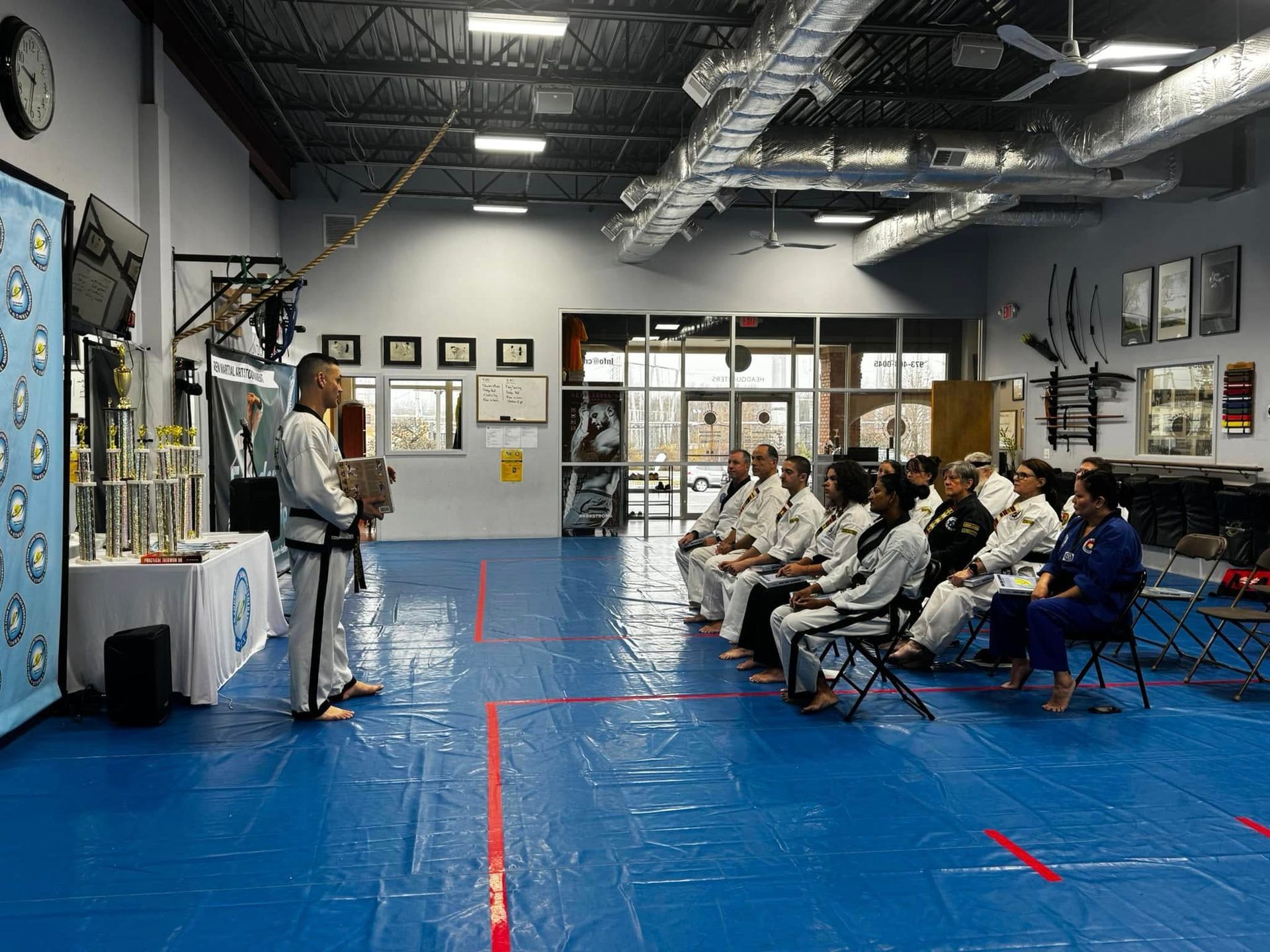 A man is standing in front of a group of people in a gym.
