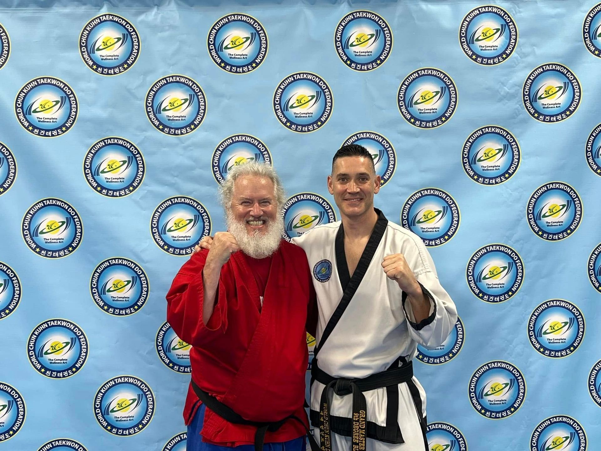 Two men are posing for a picture in front of a blue background.