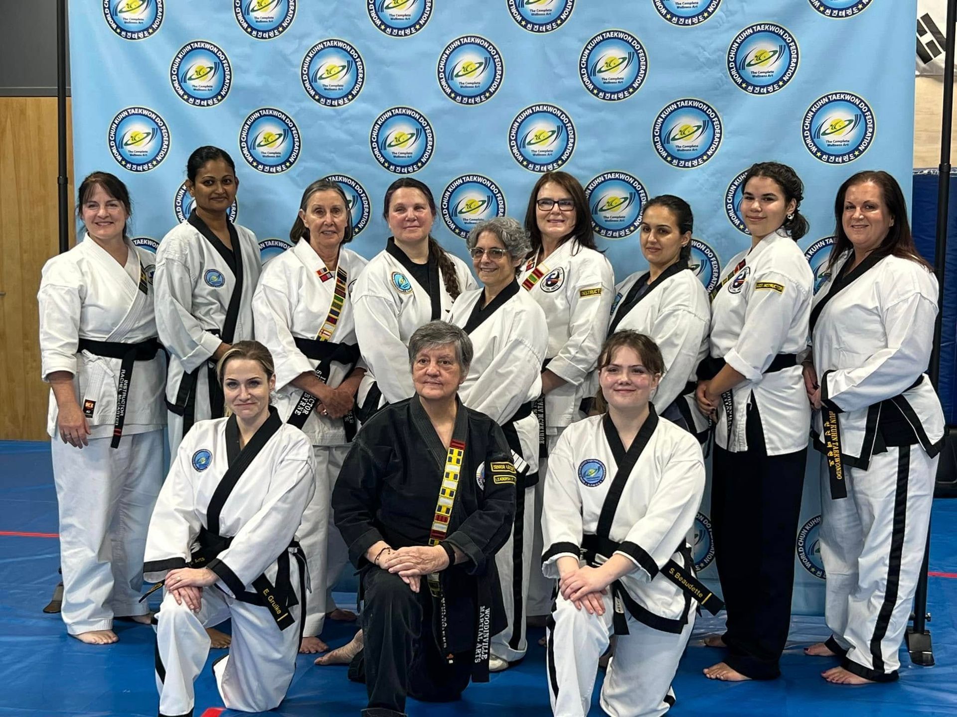 A group of women in karate uniforms are posing for a picture.