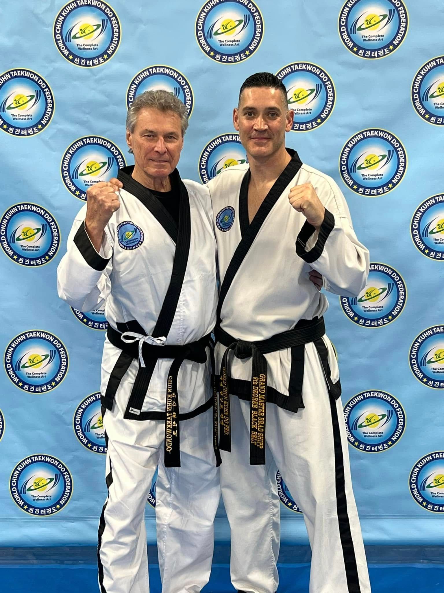 Two men in martial arts uniforms are posing for a picture.