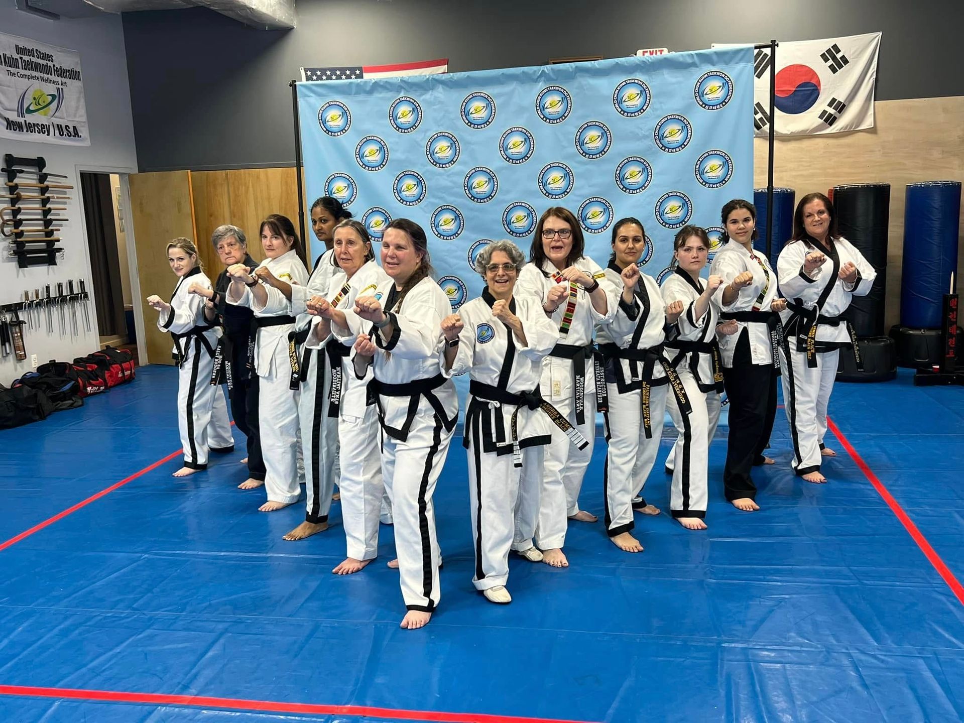 A group of women in karate uniforms are posing for a picture in a gym.