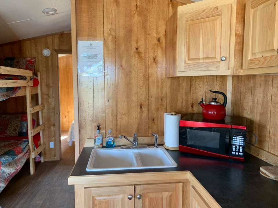 A kitchen with a sink , microwave , and bunk beds.