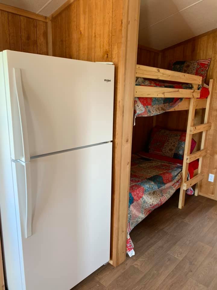 A bunk bed next to a refrigerator in a cabin.