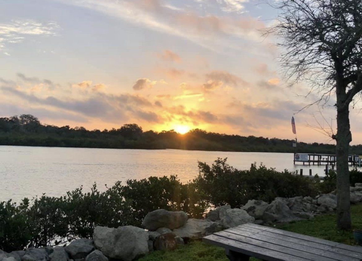 A sunset over a lake with a picnic table in the foreground