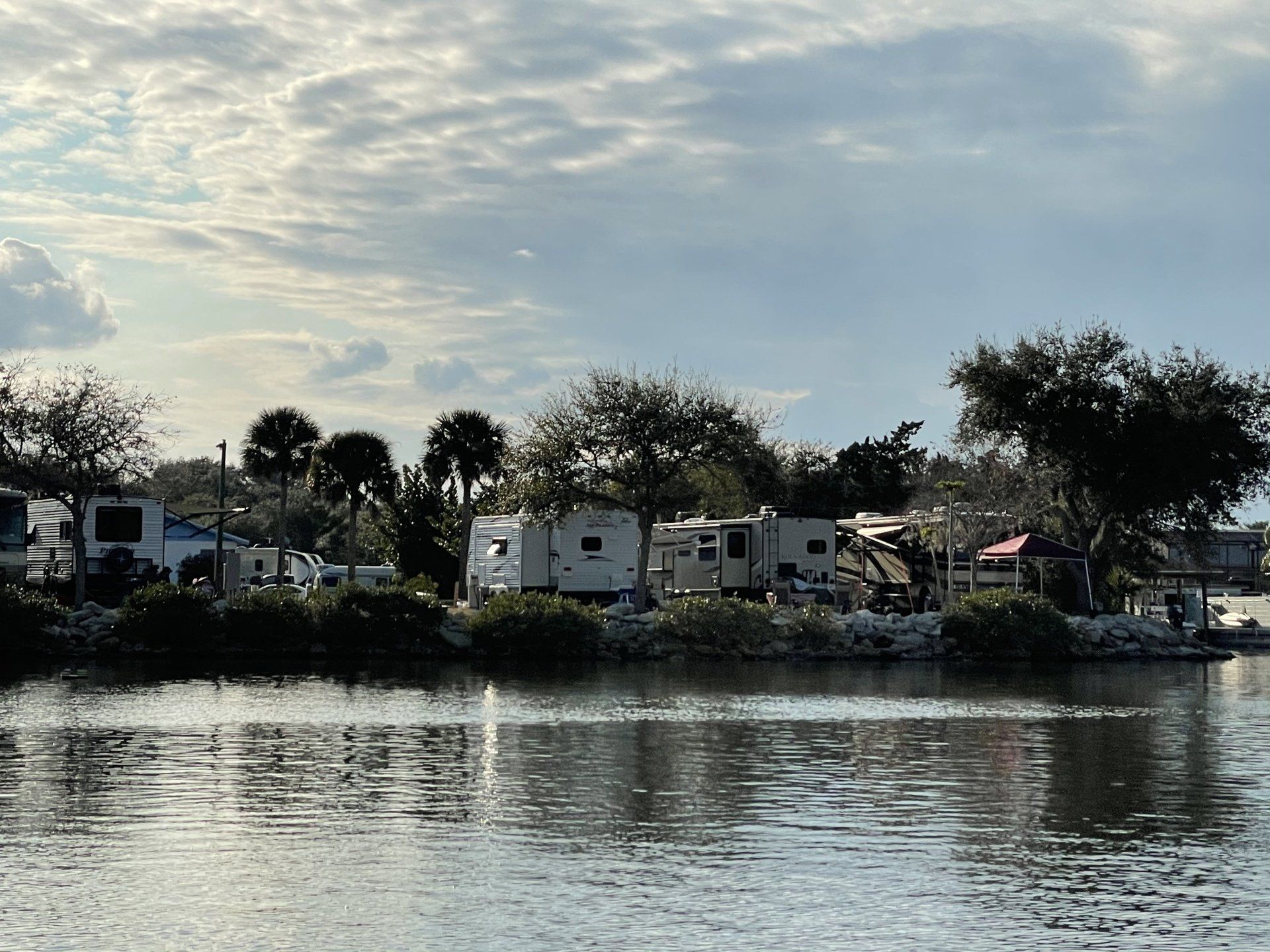 A row of rvs parked on the shore of a lake.