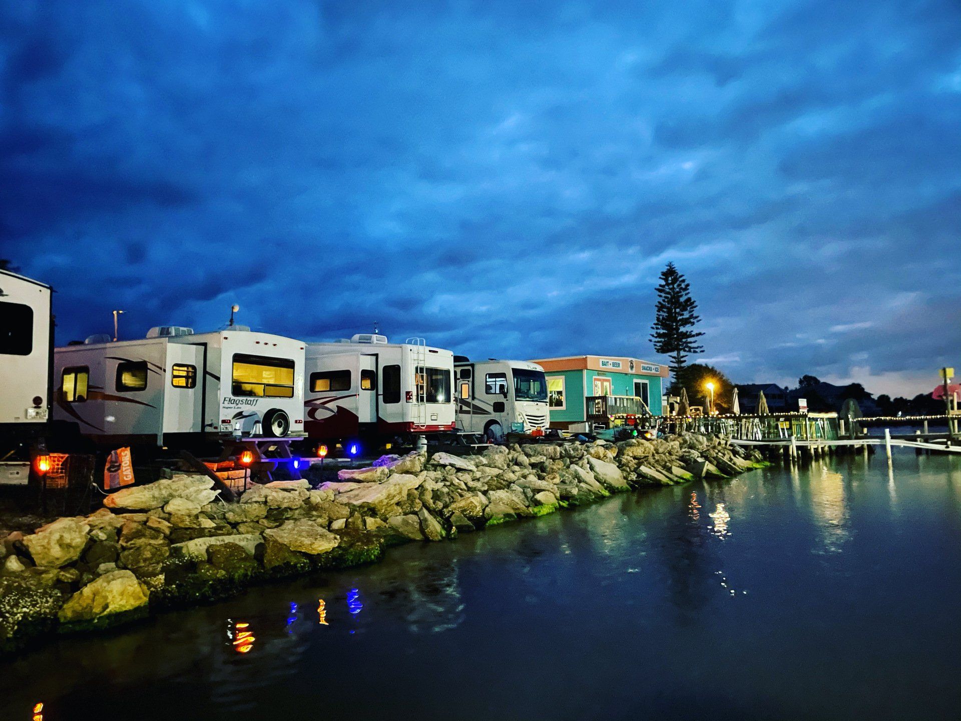 A row of rvs parked next to a body of water.