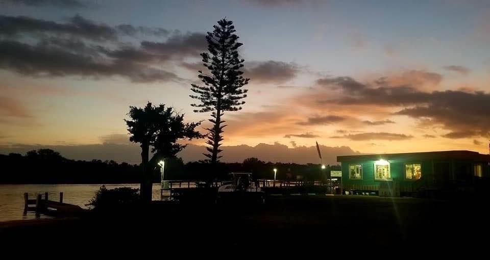 A sunset over a body of water with a house in the foreground