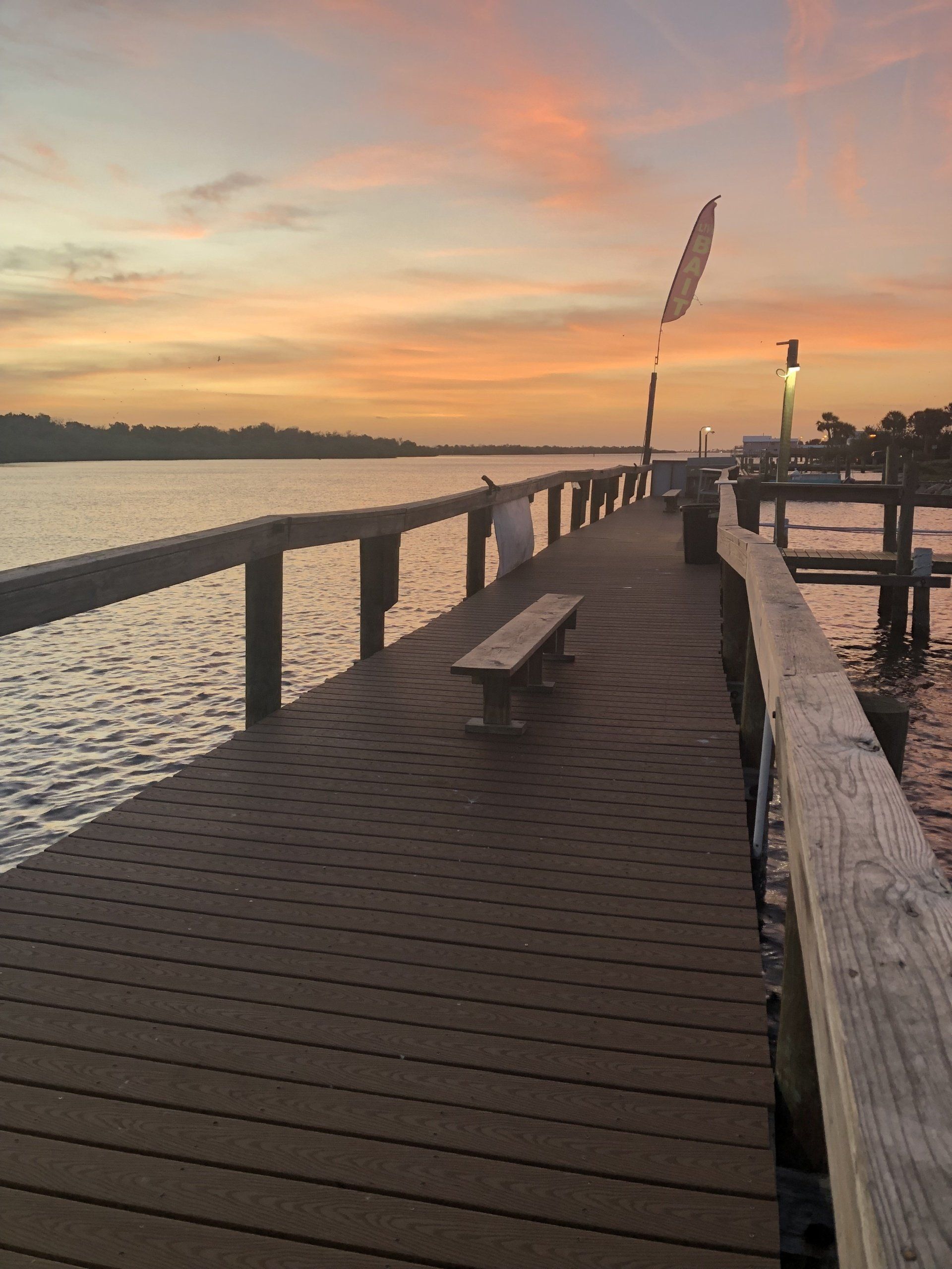A dock with a bench and a sunset in the background
