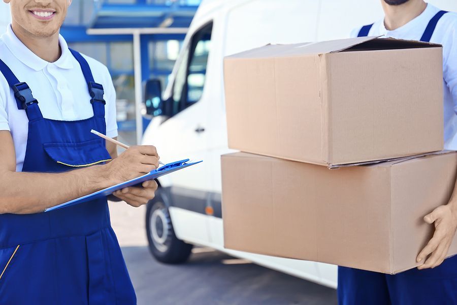 Mover writing on a clipboard while holding cardboard boxes.
