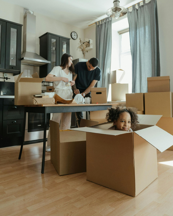 Mover in blue carrying a cardboard box toward a delivery van.