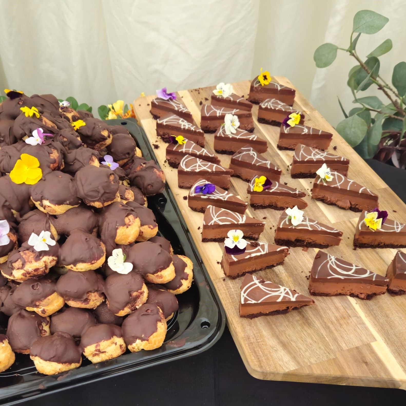 A wooden cutting board with a bunch of chocolate desserts on it