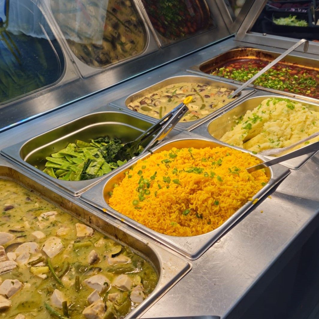 A buffet line with a variety of food including rice and vegetables