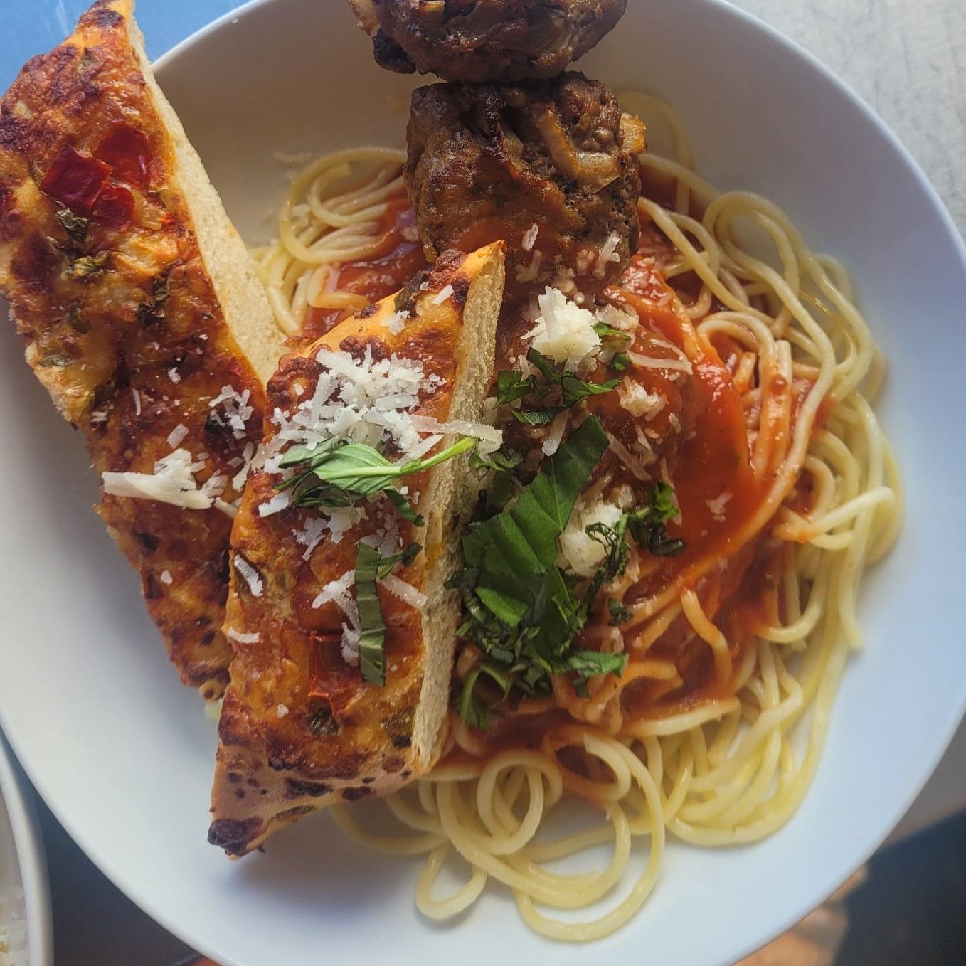 A white plate topped with spaghetti meatballs and garlic bread