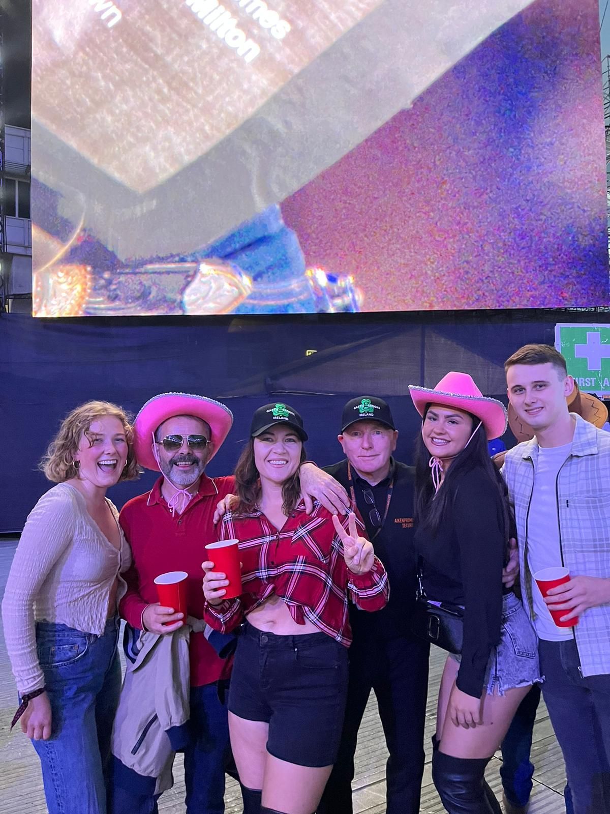 A group of people are posing for a picture in front of a large screen.