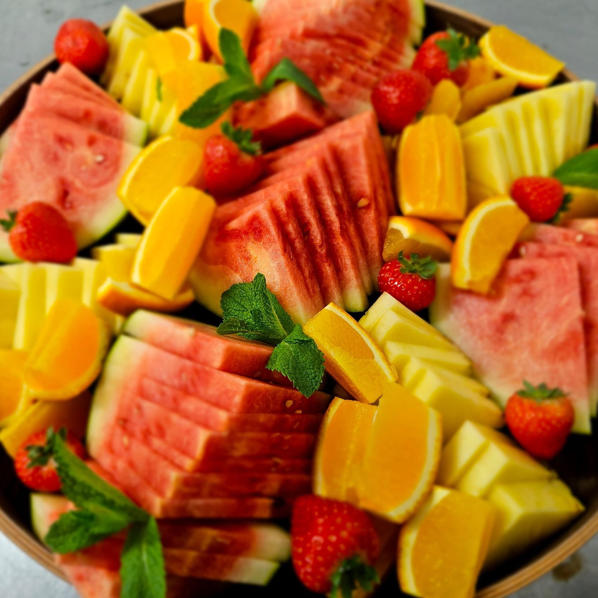 A bowl filled with sliced watermelon pineapple strawberries and oranges