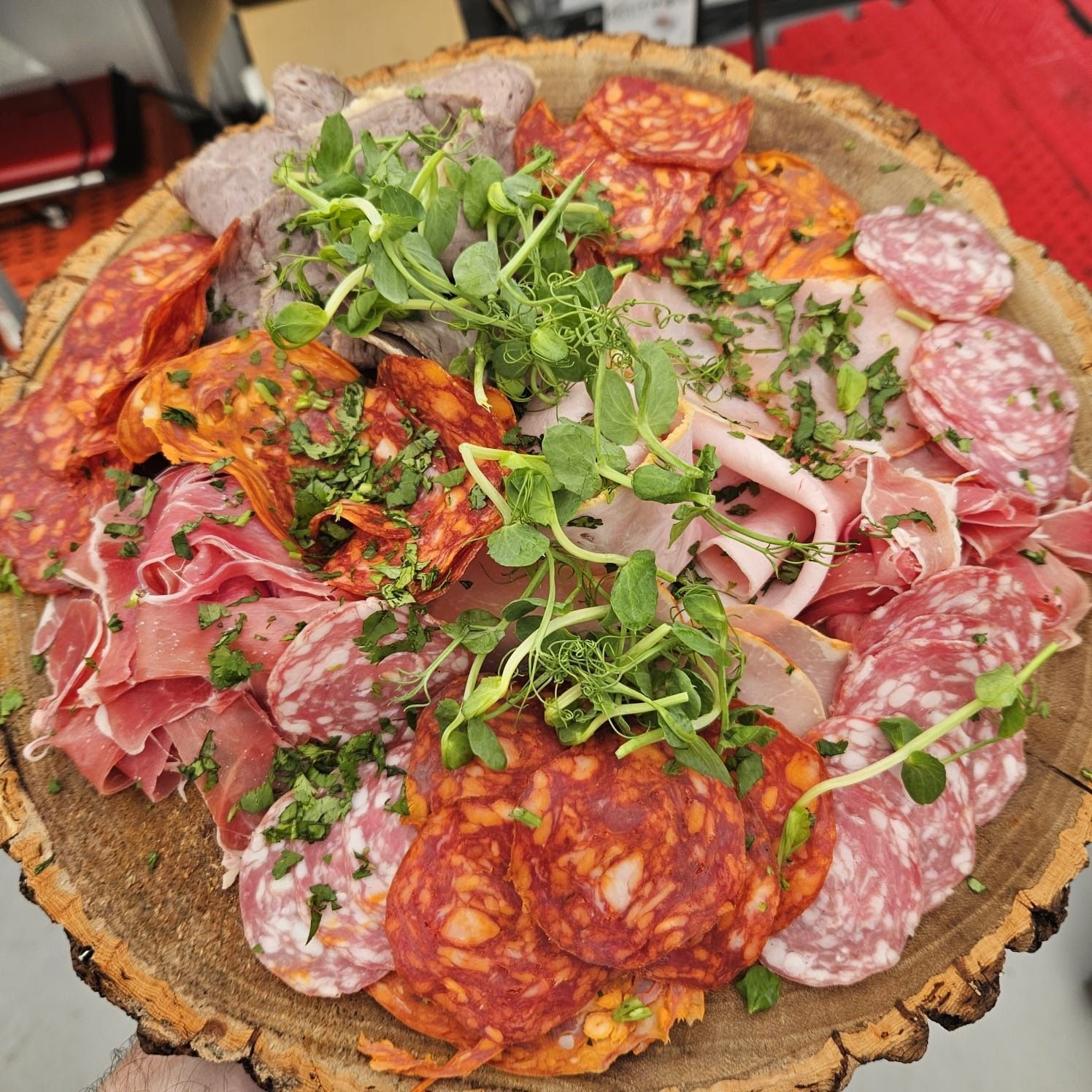 A person is holding a wooden plate with meat and vegetables on it.