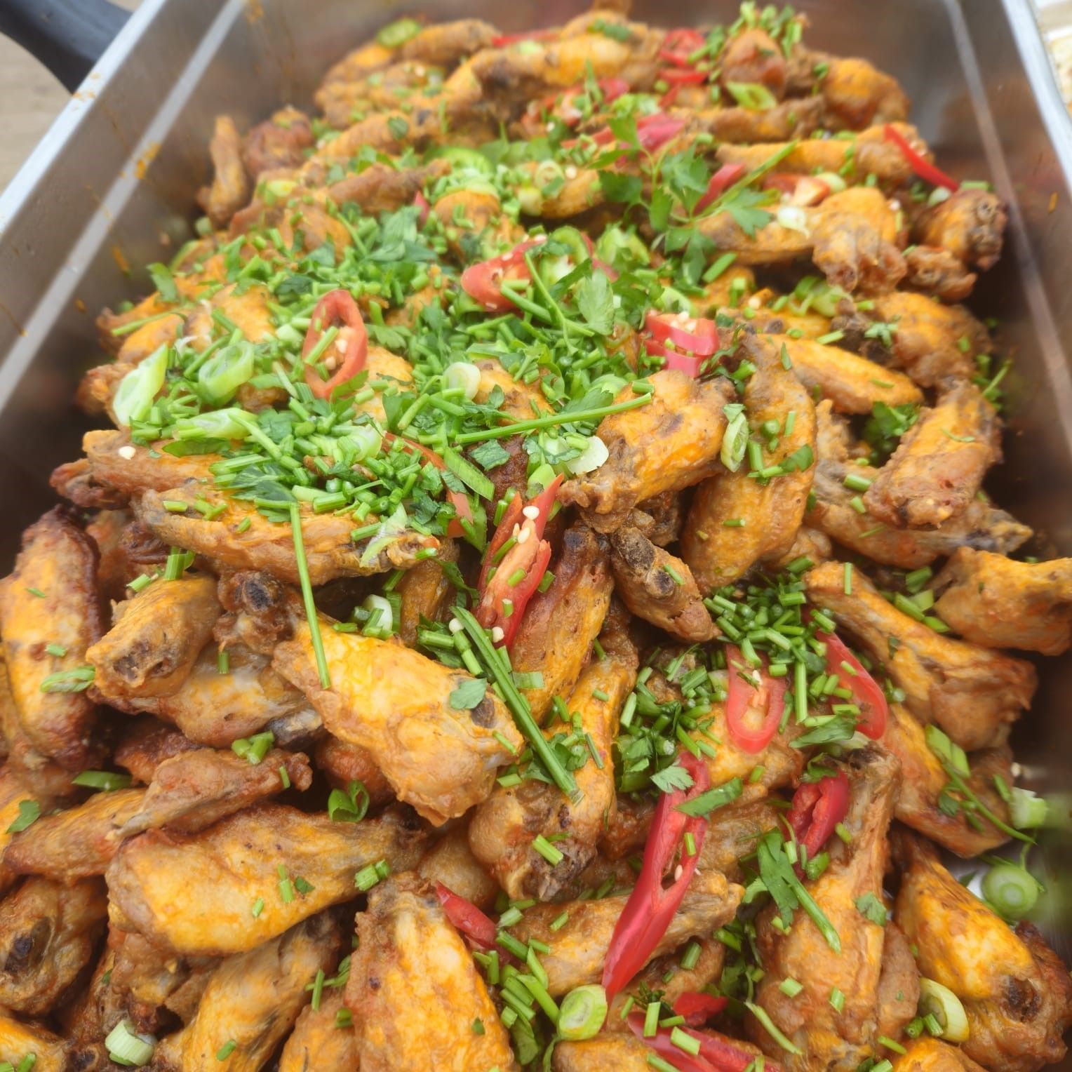 A tray of chicken wings with green onions and red peppers