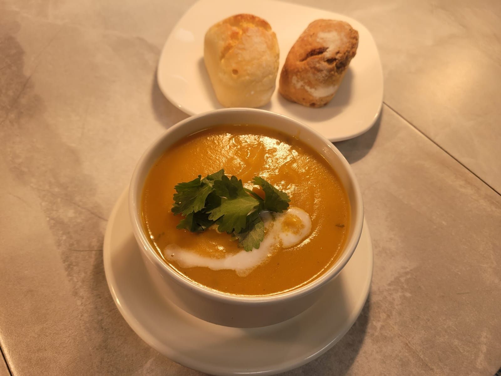 A bowl of soup next to a plate of bread