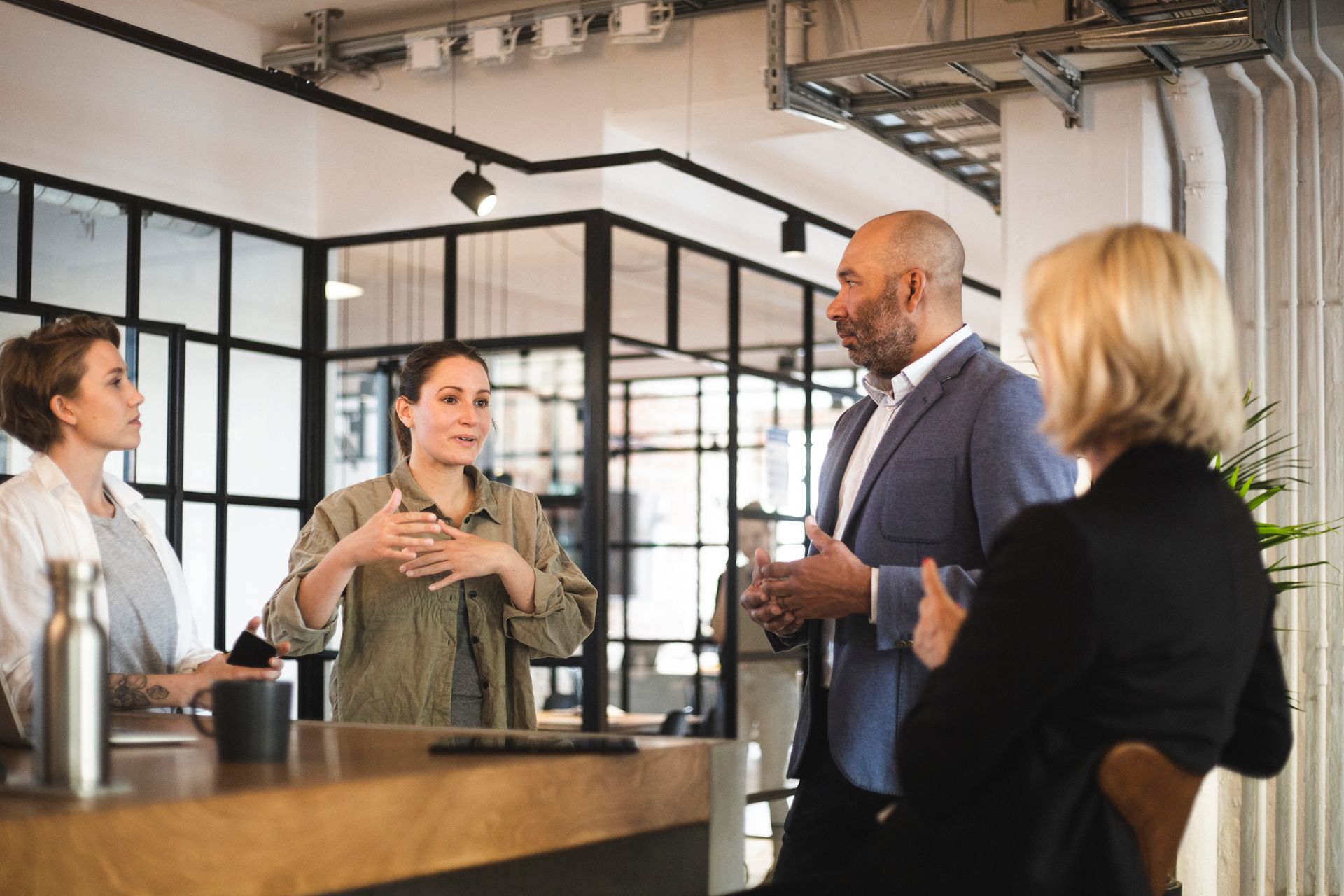 A group of people are standing around a table talking to each other.