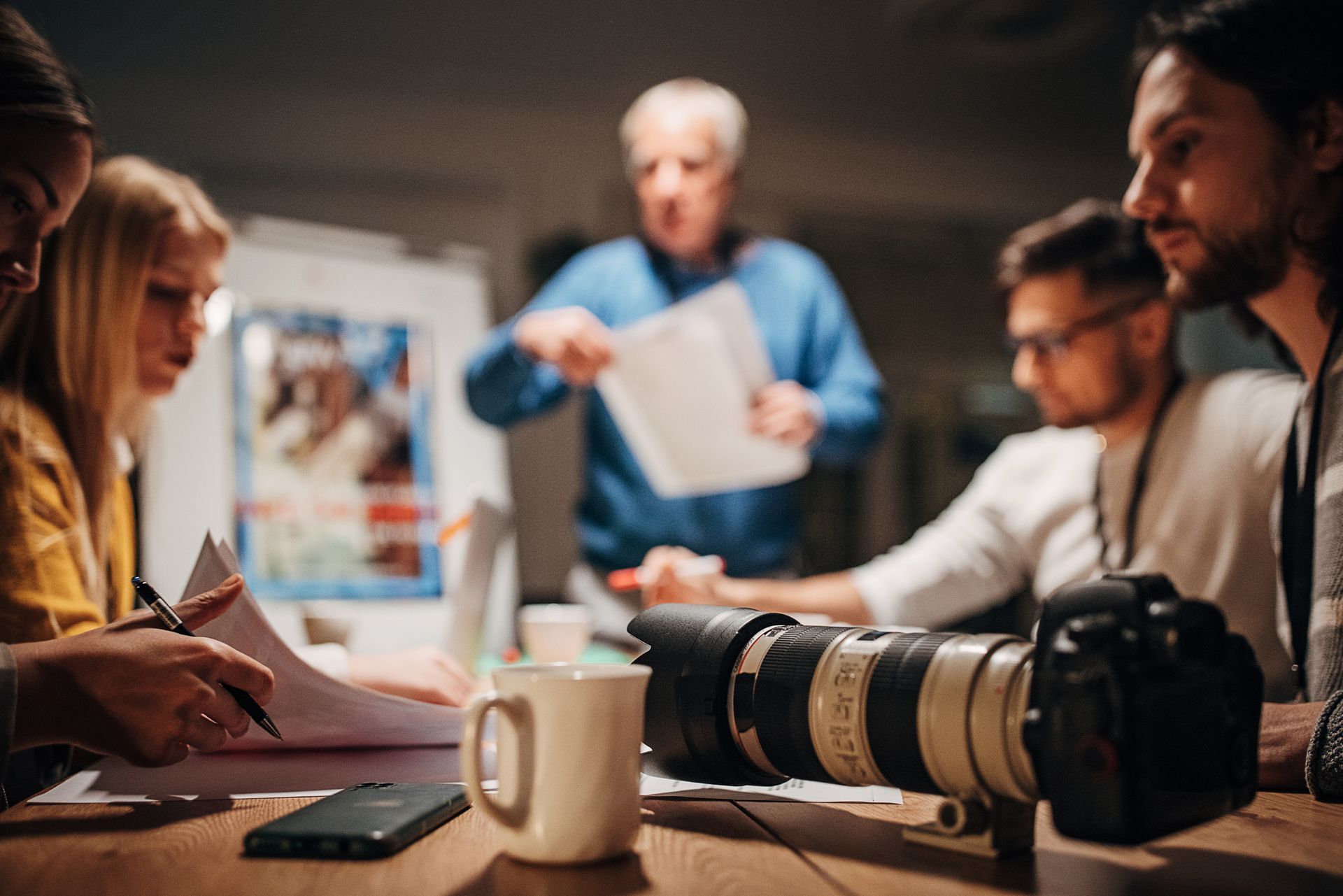 A group of people are sitting around a table with a camera on it.
