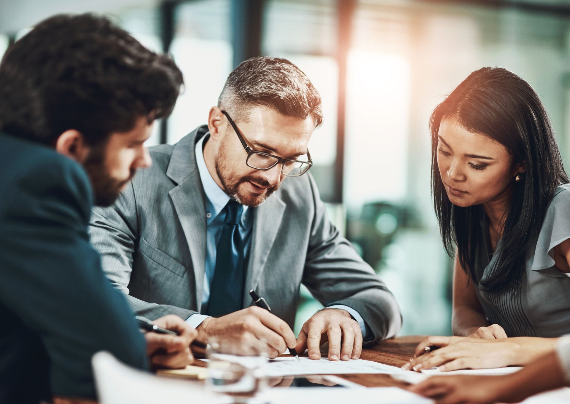 A group of business people are sitting around a table looking at a piece of paper.