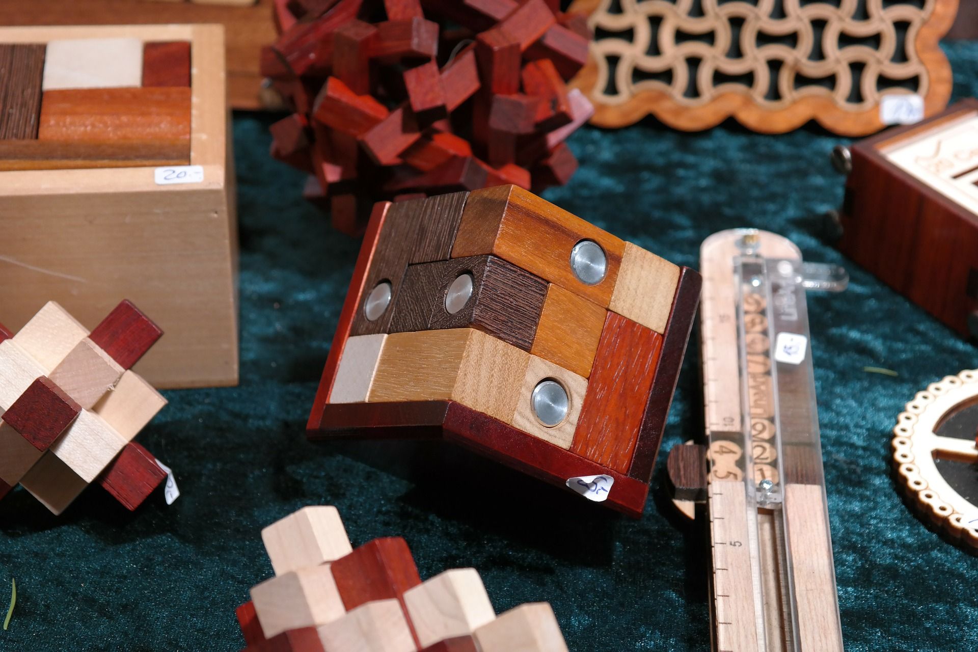 Puzzle en bois avec divers carrés aux tons de bois et des accents métalliques, entouré d'autres puzzles en bois sur une table.