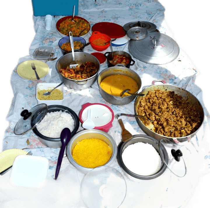 Nourriture étalée sur une nappe blanche : divers bols et pots avec du riz, des ragoûts et d'autres plats.