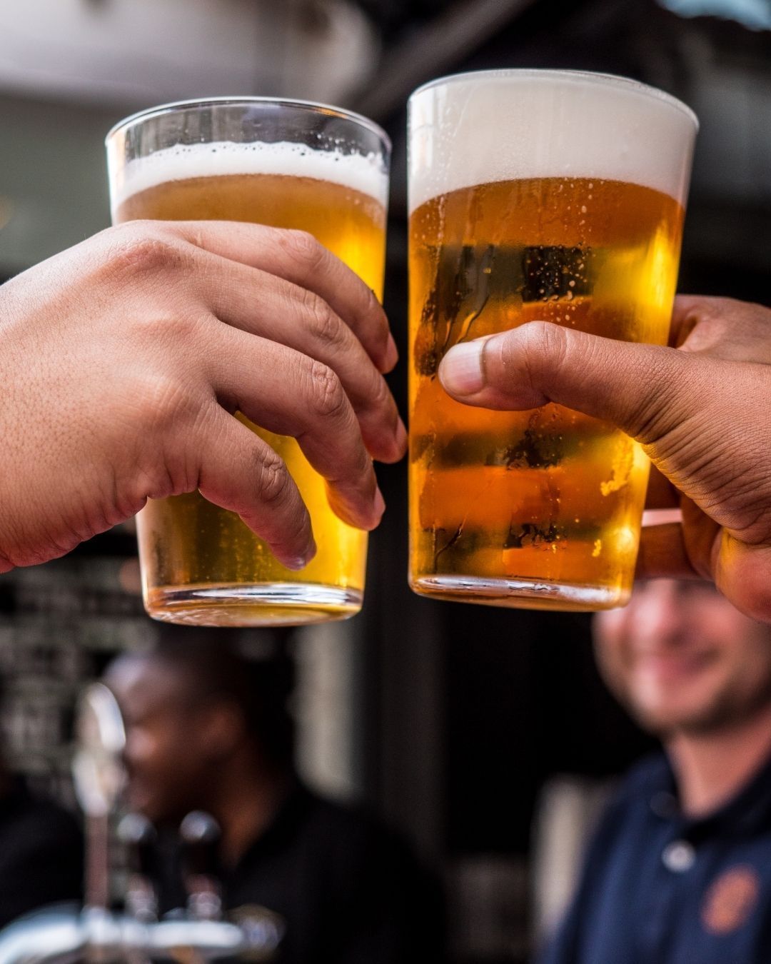 Two people clinking pints of Lone Pint craft beer in the Magnolia, TX beer garden.