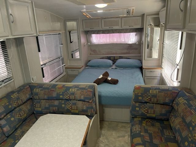 Interior of a Caravan With a Bed, Seating Area, and Overhead Cabinets — Karumba Point Holiday Tourist Park in Karumba, QLD