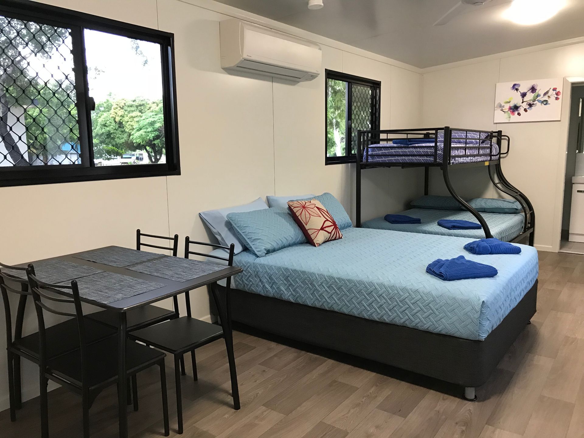 Bedroom With a Double Bed, Bunk Beds, Table, Chairs, Air Conditioner, and Two Windows — Karumba Point Holiday Tourist Park in Karumba, QLD