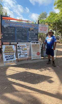 A man is standing in front of a sign that says `` book now ''.