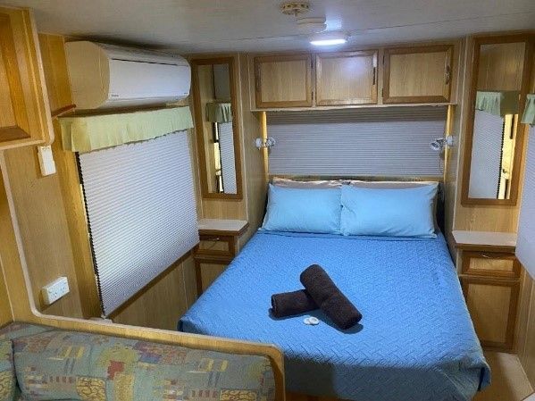Bedroom in a Caravan With a Blue Bed, Matching Linens, and Wooden Cabinets — Karumba Point Holiday Tourist Park in Karumba, QLD