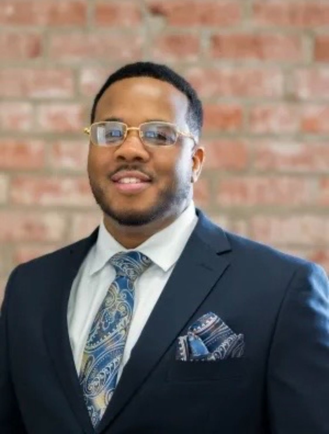 A woman is sitting at a desk with a laptop and a vase of flowers.