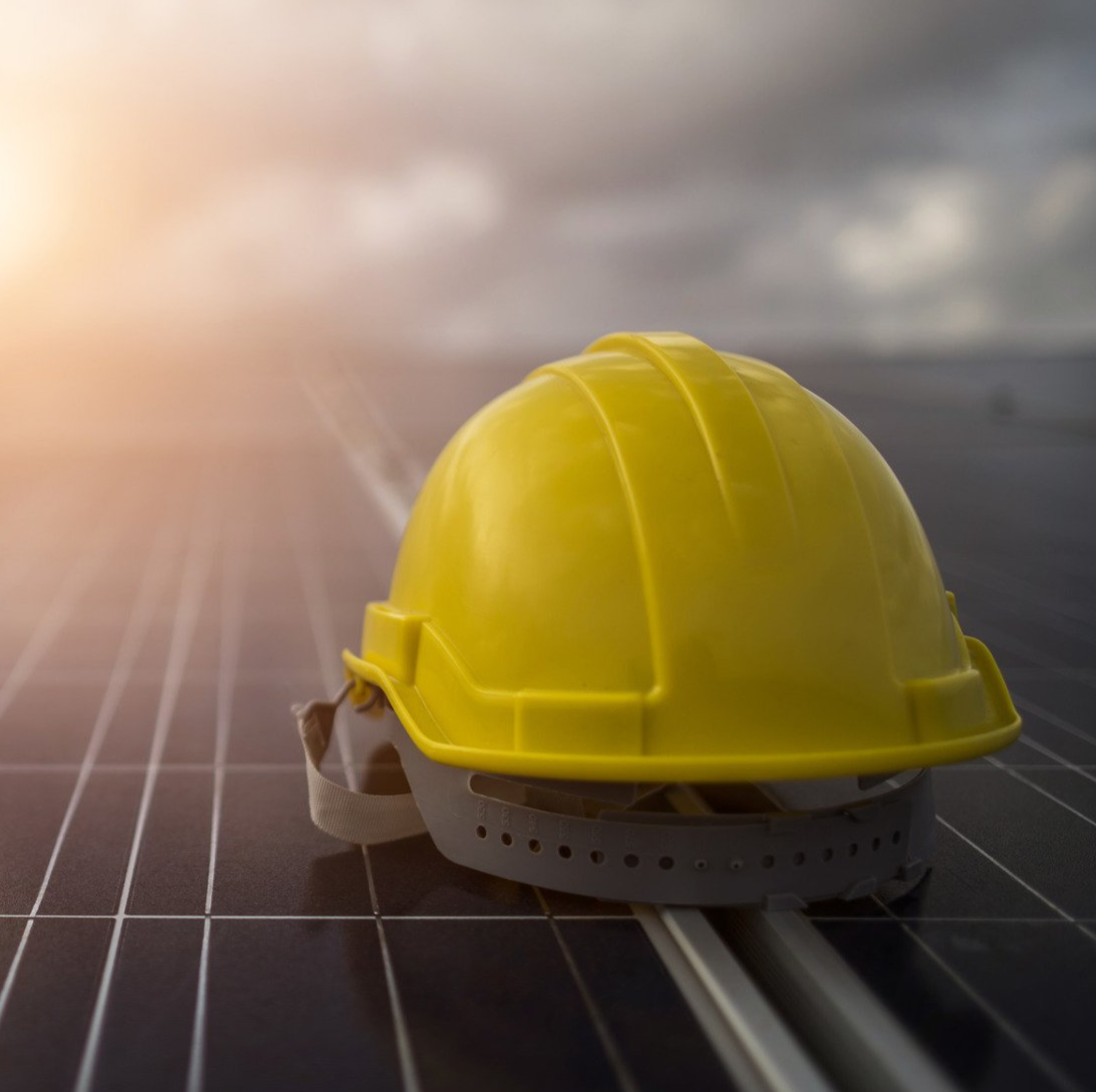 A yellow hard hat is sitting on top of a solar panel.