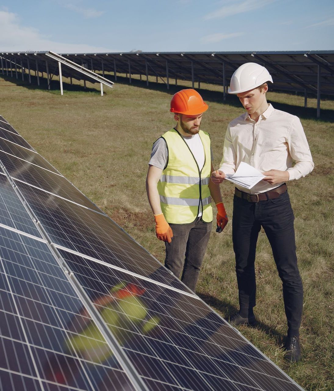 Dos hombres están parados uno al lado del otro frente a un panel solar.