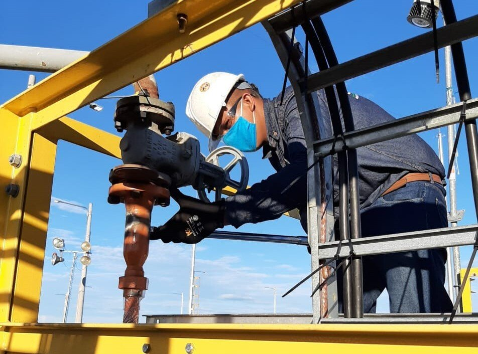 Un hombre que lleva un casco y una máscara está trabajando en una tubería.