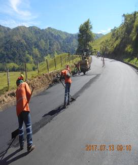 Un grupo de personas está trabajando en una carretera en las montañas.