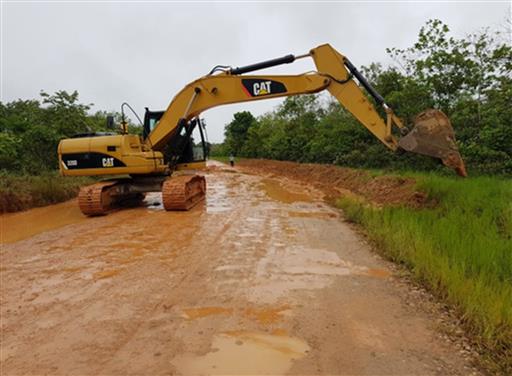 Una excavadora amarilla avanza por un camino fangoso.