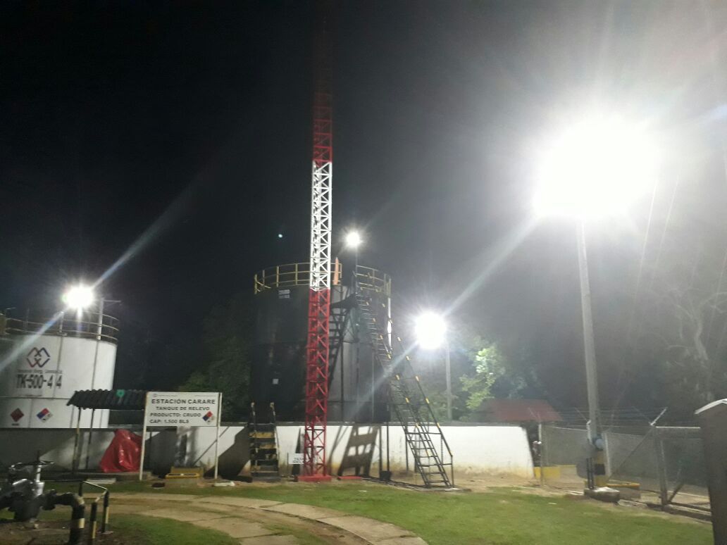 Una gran torre se ilumina por la noche en un parque.