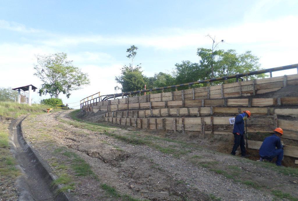 Dos hombres están trabajando en un muro de madera al costado de una carretera.